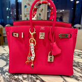 FORK & MELON SOAP AF beaded keychain charm on a bright pink designer Hermes handbag — black and white beaded detail with gold hardware and checkered heart accent, styled as a chic accessory.